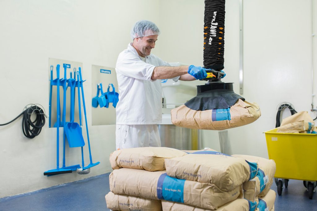 Mitarbeiter hebt Säcke mit Vakuumheber in hygienischer Produktionsumgebung