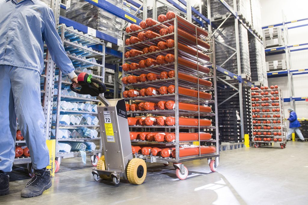 Mitarbeiter in der Lebensmittelproduktion bewegt Rollgestell mit Ziehhilfe