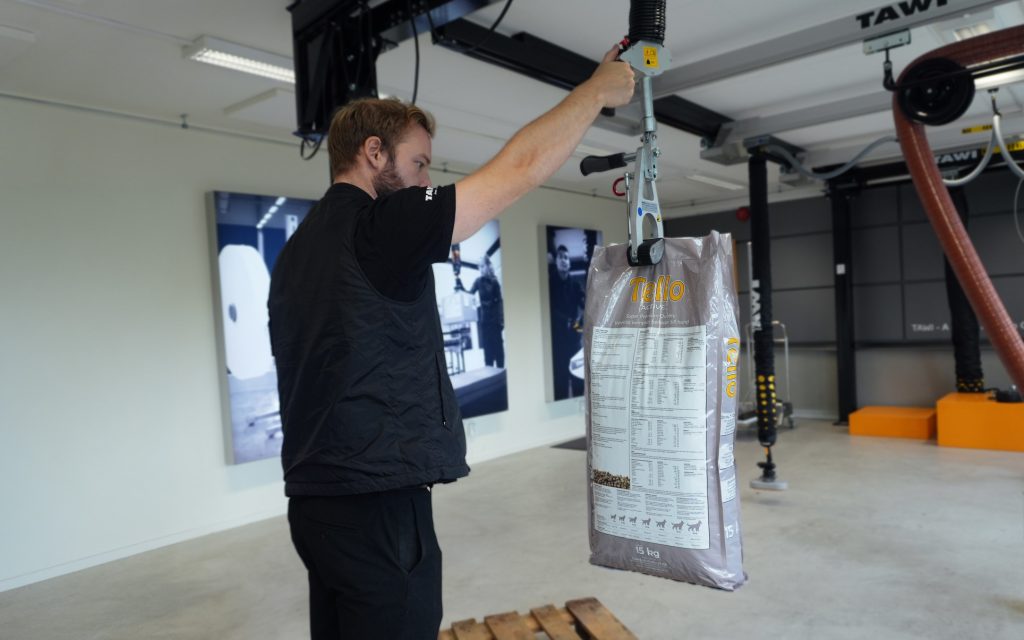 Mitarbeiter hebt mit einer TAWI-Hebehilfe einen 15-kg-Sack an.
